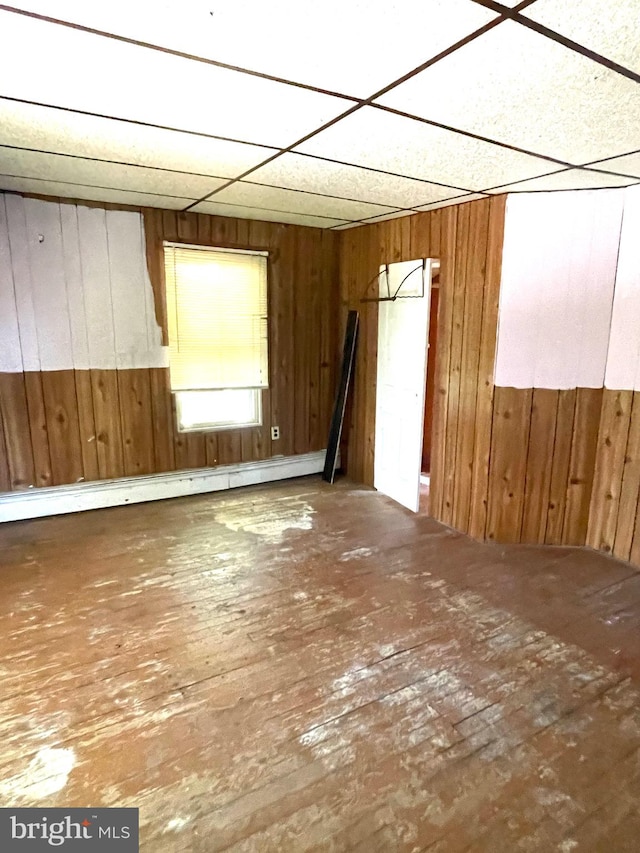 empty room with a paneled ceiling and wood walls