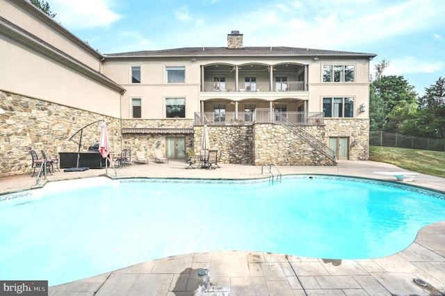 view of swimming pool featuring a diving board and a patio