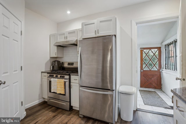 kitchen with stainless steel appliances, white cabinets, dark stone countertops, and dark wood-type flooring