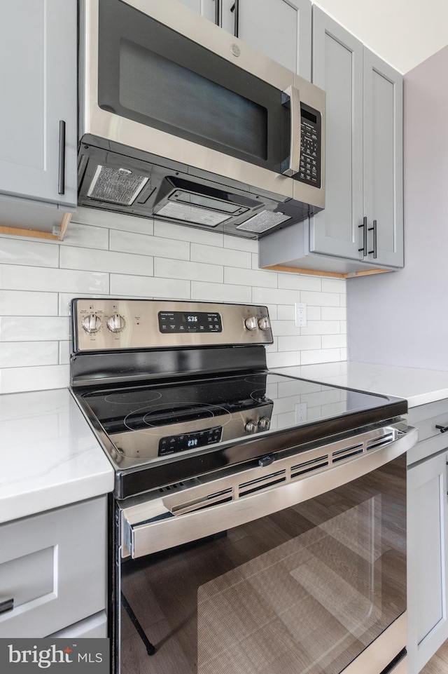 kitchen featuring appliances with stainless steel finishes, backsplash, and gray cabinetry