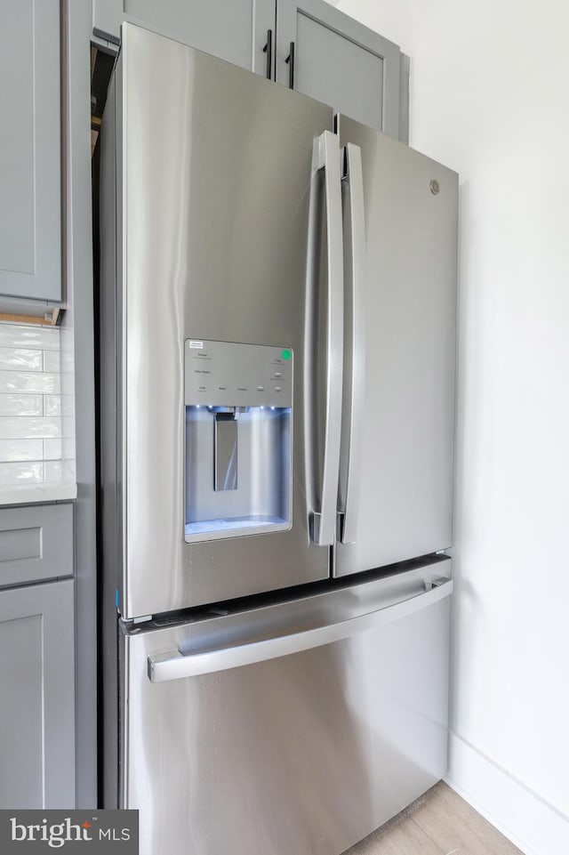 kitchen with light hardwood / wood-style flooring, stainless steel fridge, gray cabinets, and decorative backsplash