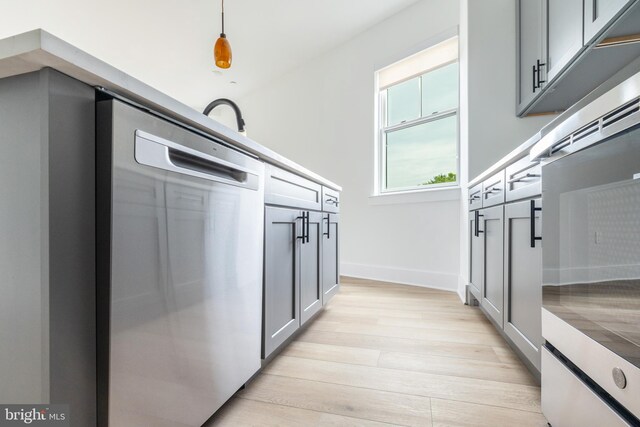 kitchen featuring light wood-type flooring, pendant lighting, and gray cabinets