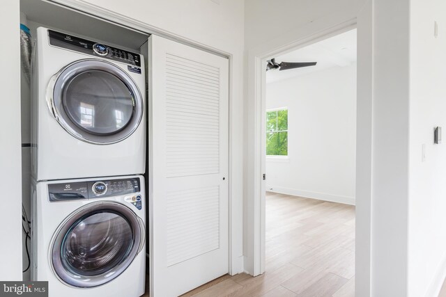 washroom with stacked washing maching and dryer and light hardwood / wood-style flooring