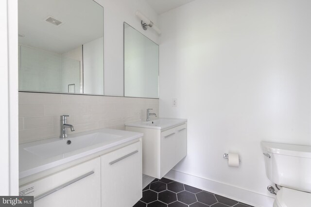 bathroom featuring tile patterned floors, backsplash, toilet, and vanity