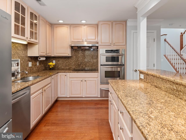 kitchen with sink, appliances with stainless steel finishes, tasteful backsplash, light hardwood / wood-style floors, and light stone counters