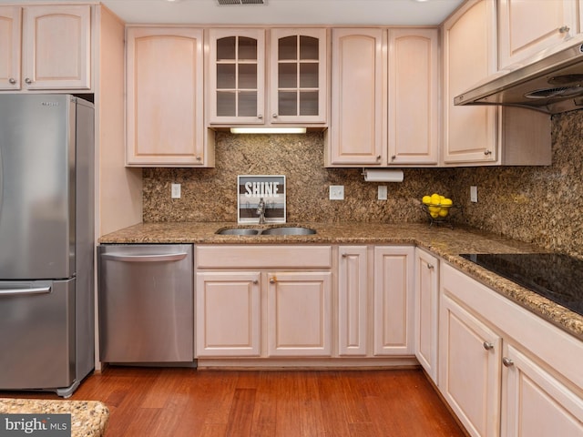 kitchen with decorative backsplash, stone counters, sink, and stainless steel appliances