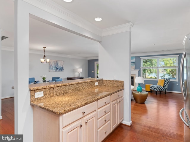 kitchen featuring light stone countertops, stainless steel fridge, crown molding, a chandelier, and dark hardwood / wood-style floors