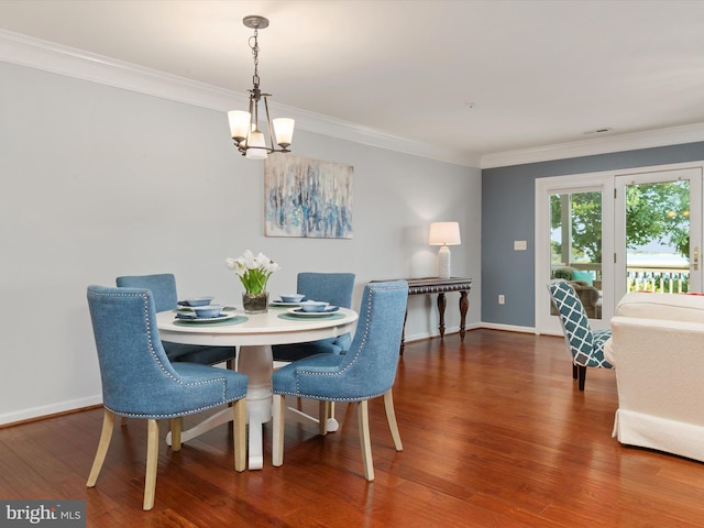 dining area with hardwood / wood-style floors, ornamental molding, and an inviting chandelier