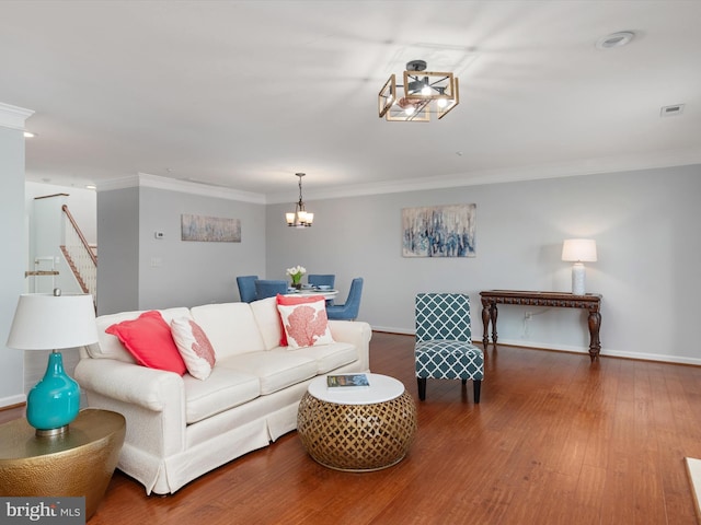 living room with a notable chandelier, wood-type flooring, and ornamental molding