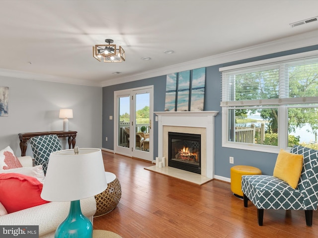 living room with a chandelier, wood-type flooring, crown molding, and a healthy amount of sunlight