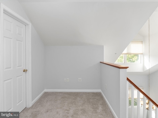 additional living space featuring light colored carpet and vaulted ceiling