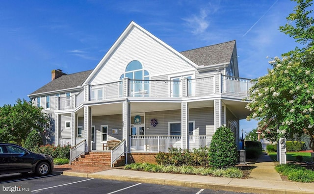 view of front of property featuring a porch, a balcony, and central air condition unit