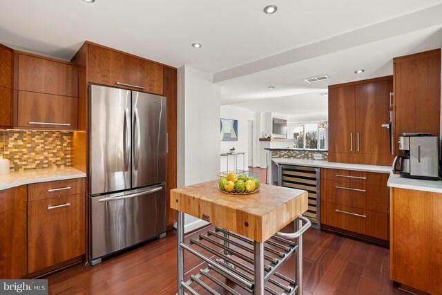 kitchen with dark wood finished floors, wine cooler, brown cabinets, and freestanding refrigerator