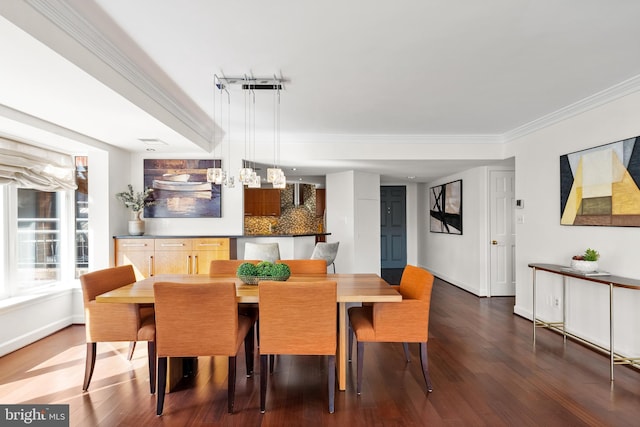 dining room with baseboards, wood finished floors, and crown molding