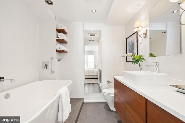 ensuite bathroom featuring toilet, ensuite bathroom, tile patterned flooring, a freestanding bath, and vanity