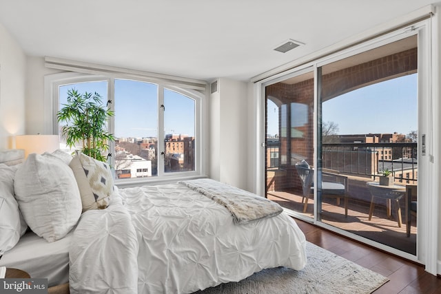 bedroom with access to exterior, visible vents, dark wood-style flooring, and expansive windows