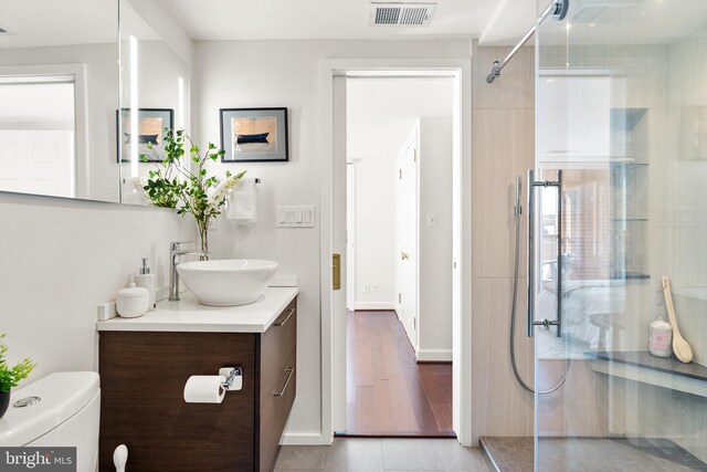 full bath featuring visible vents, toilet, a walk in shower, wood finished floors, and vanity