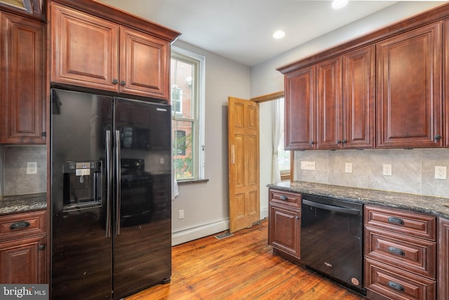 kitchen with decorative backsplash, black appliances, dark stone counters, and light hardwood / wood-style floors