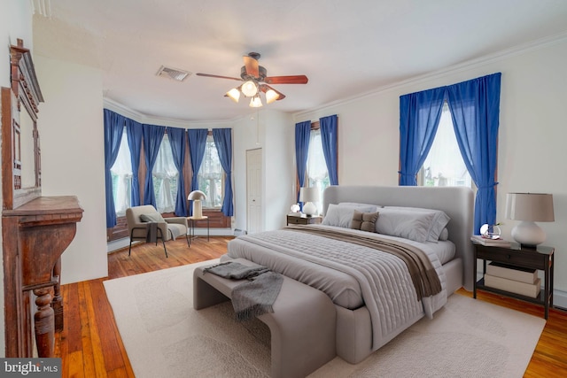 bedroom with wood-type flooring, ornamental molding, and ceiling fan