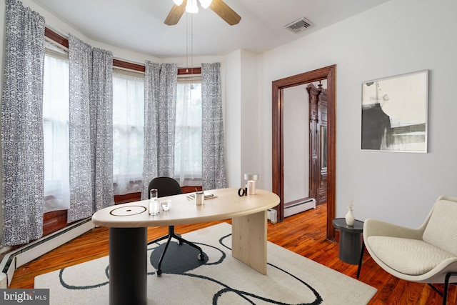 office featuring baseboard heating, wood-type flooring, and ceiling fan