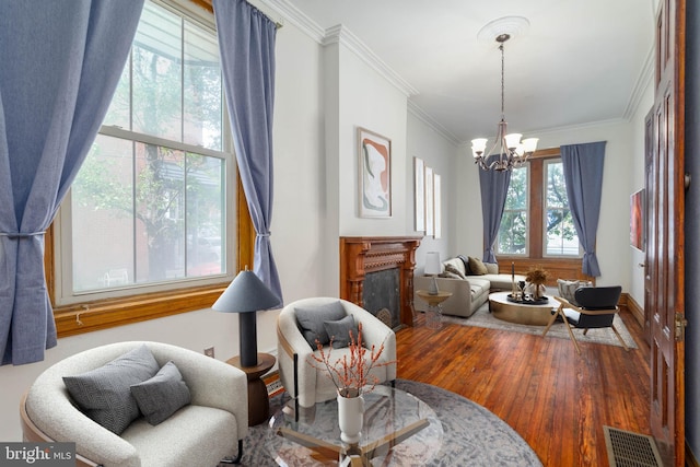 living area featuring hardwood / wood-style flooring, a chandelier, and crown molding