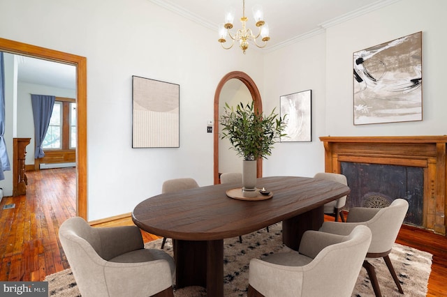 dining room featuring ornamental molding, baseboard heating, hardwood / wood-style floors, and a notable chandelier