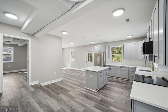 kitchen with gray cabinetry, appliances with stainless steel finishes, light wood-type flooring, and a center island