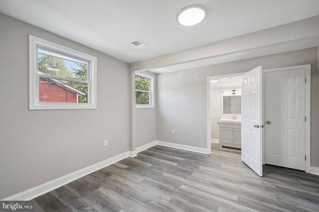 unfurnished bedroom featuring light wood-type flooring and ensuite bathroom