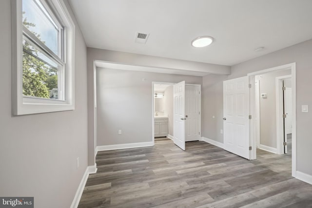 unfurnished bedroom with hardwood / wood-style flooring and ensuite bathroom