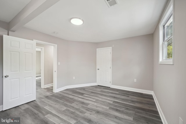 spare room featuring beam ceiling and hardwood / wood-style floors