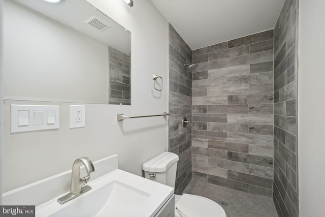 bathroom with tiled shower, vanity, and toilet