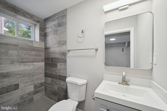 bathroom with vanity, toilet, and tiled shower