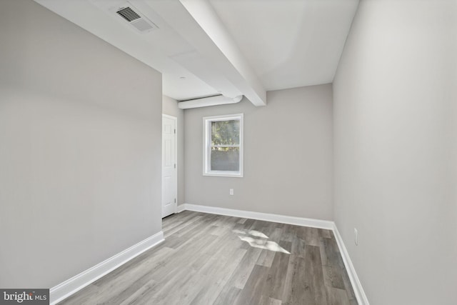 unfurnished room featuring light hardwood / wood-style floors and beamed ceiling