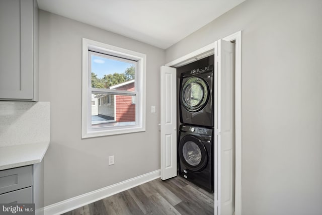 clothes washing area with dark wood-type flooring and stacked washing maching and dryer