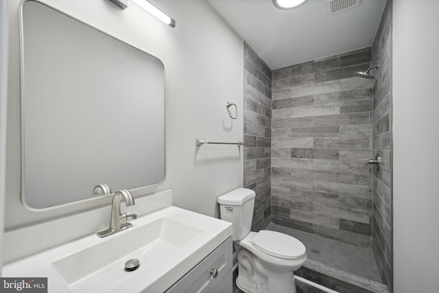 bathroom with tiled shower, vanity, and toilet