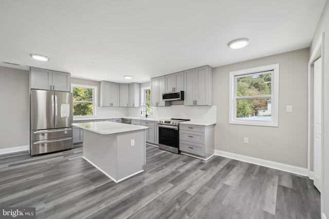 kitchen featuring sink, gray cabinetry, appliances with stainless steel finishes, a center island, and dark hardwood / wood-style flooring