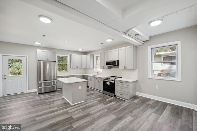 kitchen with appliances with stainless steel finishes, a healthy amount of sunlight, and a center island