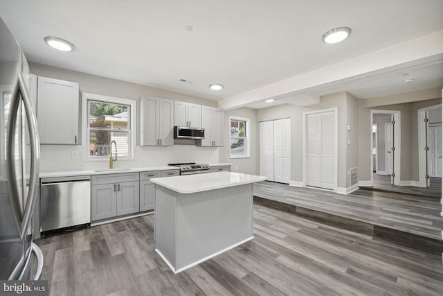 kitchen featuring stainless steel appliances, hardwood / wood-style flooring, a kitchen island, and sink