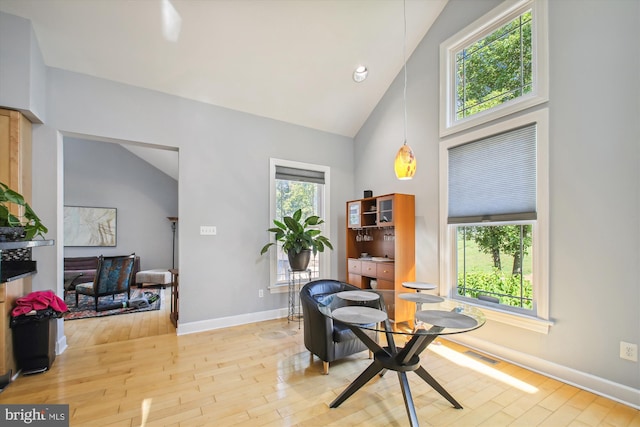 living area with high vaulted ceiling and light wood-type flooring