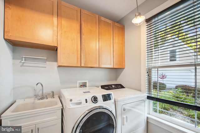 laundry area with a healthy amount of sunlight, sink, washer and clothes dryer, and cabinets