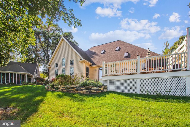 back of property with a deck and a yard