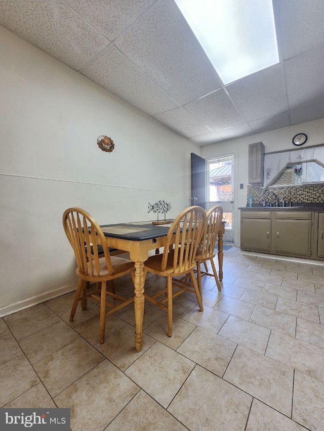 tiled dining space featuring a paneled ceiling and sink