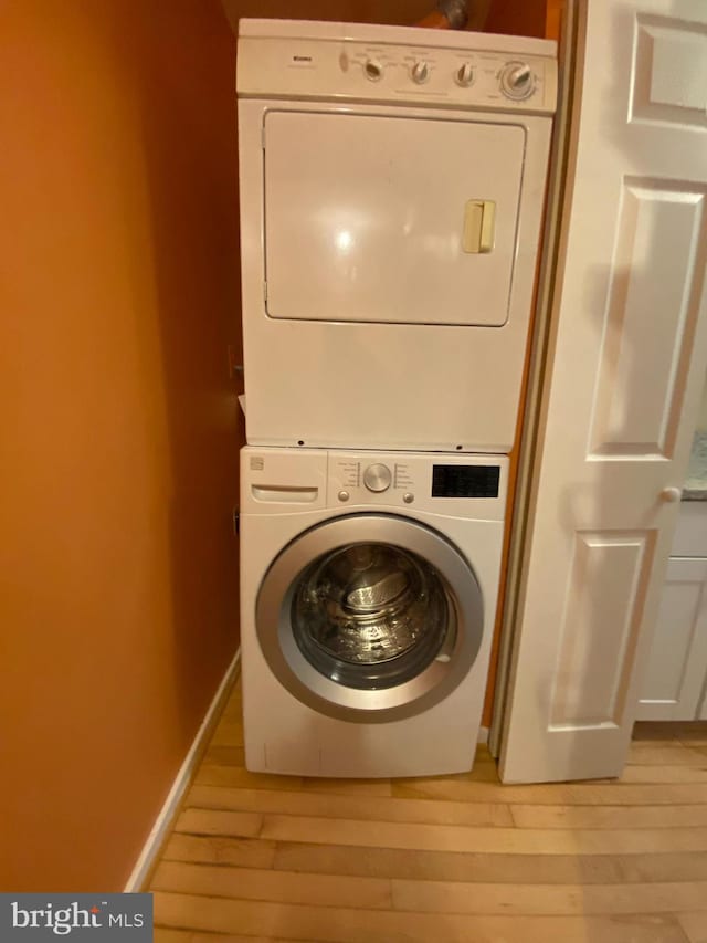 clothes washing area featuring light hardwood / wood-style floors and stacked washer / drying machine