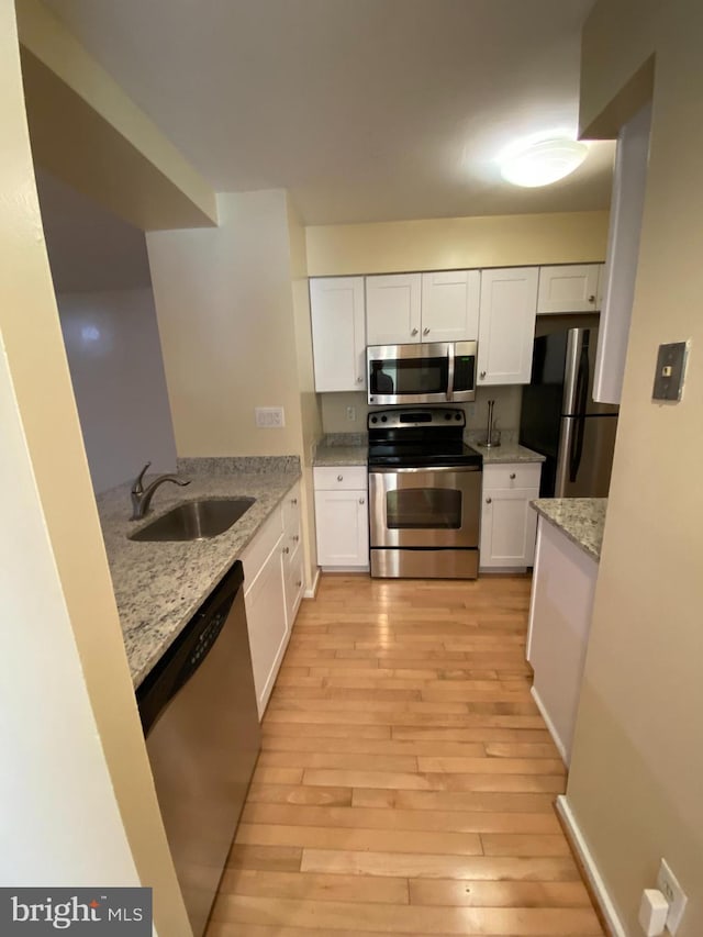 kitchen featuring stainless steel appliances, sink, and white cabinetry