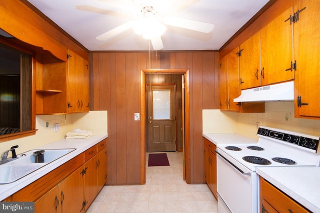 kitchen featuring wood walls, sink, ceiling fan, and electric range