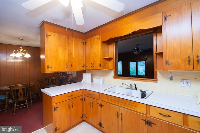 kitchen featuring hanging light fixtures, sink, ceiling fan with notable chandelier, and tasteful backsplash