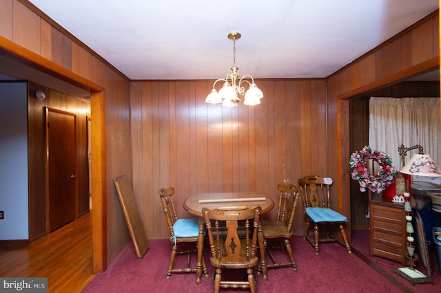 dining space with crown molding, wood walls, and a notable chandelier