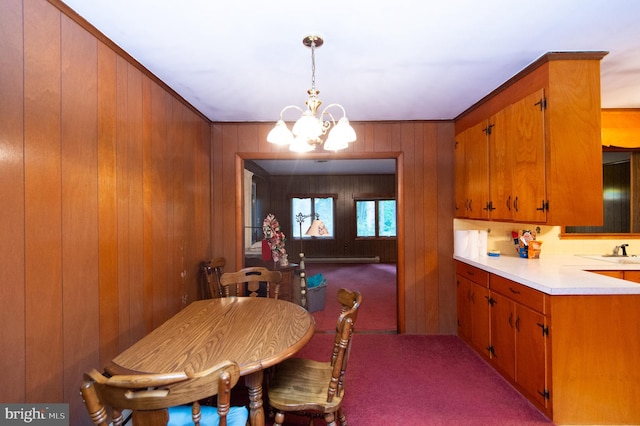 carpeted dining room with wood walls, a notable chandelier, and sink