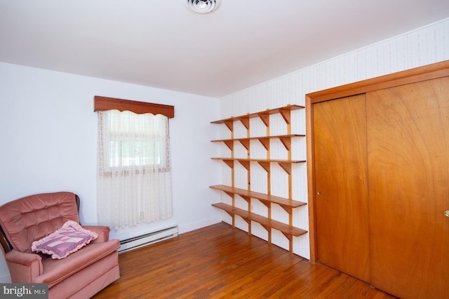 unfurnished room featuring wood-type flooring and baseboard heating