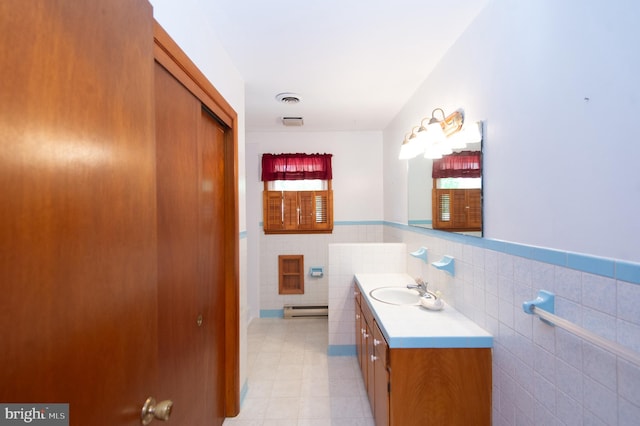 bathroom featuring a baseboard heating unit, vanity, tile walls, and decorative backsplash